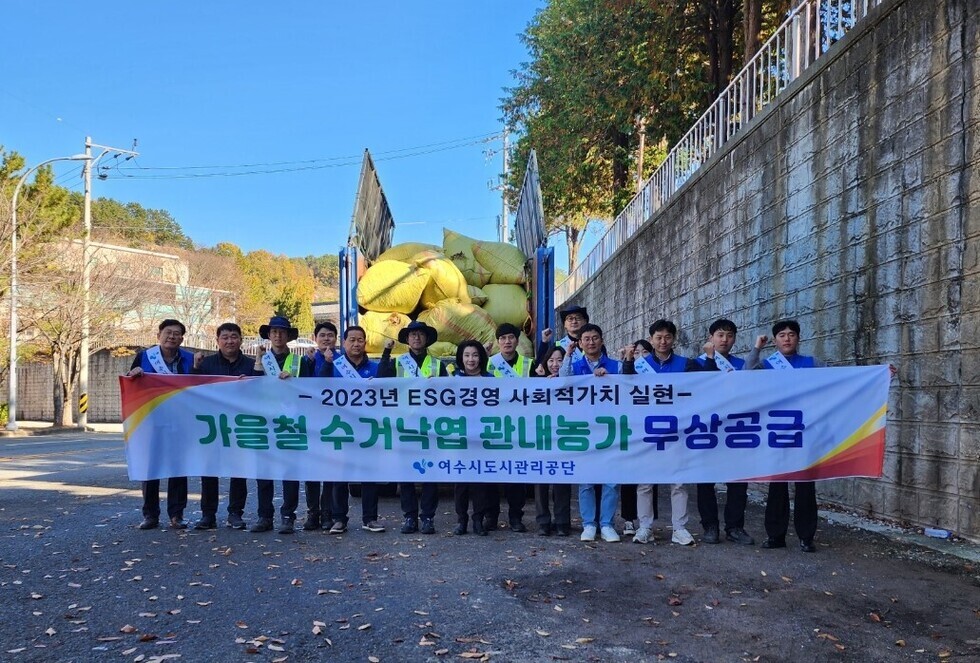 2023년 ESC 경영 사회적 가치 실현 / 가을철 수거낙엽 관내농가 무상공급 / 여수시도시관리공단 현수막 뒤에 사람들이 서 있는 모습