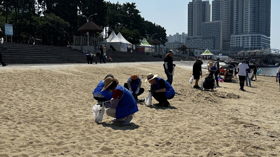 해변가에 쓰레기를 줍고 있는 사람들 모습