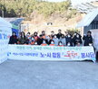 ‘따뜻한 가치, 섬세한 서비스, 든든한 도시관리공단 여수시도시관리공단 노·사 합동 동행 봉사단’이라는 문구가 적힌 현수막을 들고 여수시도시관리공단 임직원들이 김장 나눔 봉사활동을 기념하며 단체 사진을 촬영한 모습이다. 다양한 연령대의 임직원 20여 명이 모였으며, 일부는 오렌지색 앞치마와 마스크를 착용한 상태로, 김장박스가 가득 실린 트럭과 텐트 옆에서 밝은 표정으로 포즈를 취하고 있다. 