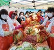 ‘따뜻한 가치, 섬세한 서비스, 든든한 도시관리공단 여수시도시관리공단 노·사 합동 동행 봉사단’이라는 문구가 적힌 현수막을 들고 여수시도시관리공단 임직원들이 김장 나눔 봉사활동을 기념하며 단체 사진을 촬영한 모습이다. 다양한 연령대의 임직원 20여 명이 모였으며, 일부는 오렌지색 앞치마와 마스크를 착용한 상태로, 김장박스가 가득 실린 트럭과 텐트 옆에서 밝은 표정으로 포즈를 취하고 있다. 