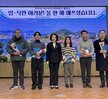 '2024년 여수시도시관리공단 종무식 임·직원 여러분! 올 한 해 애쓰셨습니다. 여수시도시관리공단 일자 : 2024.21.31 (화)'라는 문구가 적힌 대형 화면을 배경으로 같은 문구가 적혀진 현수막을 들고 여수시도시관리공단 임직원들이 단체로 촬영한 기념사진이다. 사진에는 30여 명의 임직원이 참여했으며 연령대는 20대에서 60대까지 다양하다. 2명의 남자 직원의 현수막을 길에 펼치며 앉아 있고, 가운데에는 50대 남성과 여성이 나란히 서 있으며, 전체적으로 단정한 복장으로 정돈된 분위기 속에서 한 해의 마무리를 기념하고 있다.