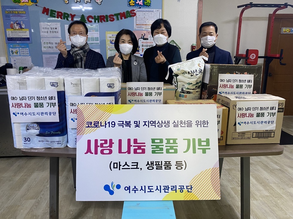 '코로나19 극복 및 지역상생 실천을 위한 사랑나눔 물품기부(마스크,생필품 등) 여수시도시관리공단' 이라고 적힌 팻말과 기부물품 앞에서 기념촬영을 하고있는 김유화 이사장과 사랑의 열매 관계자들의 기념촬영 모습