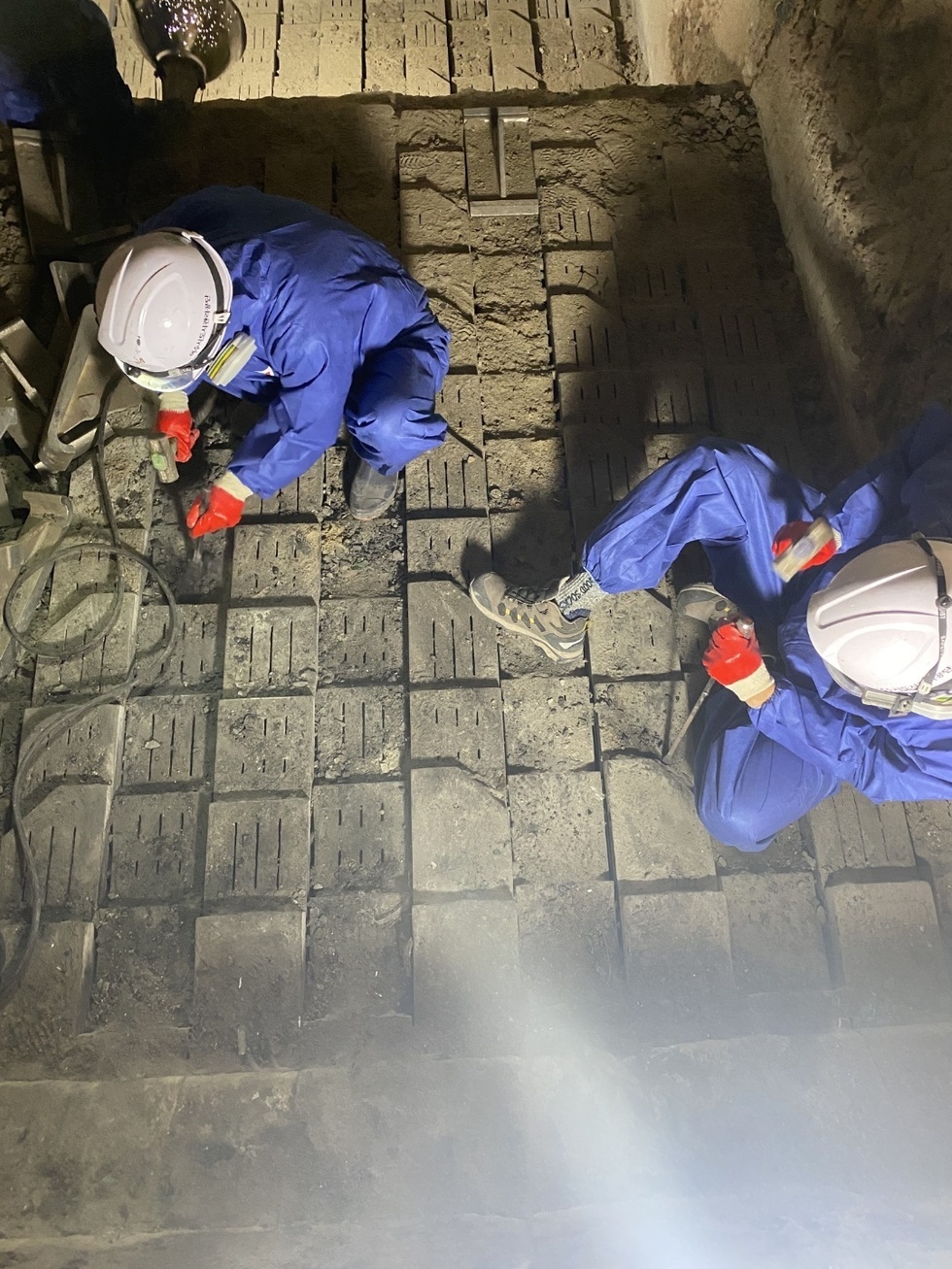 작업자 두사람이 공구를 들고 앉아서 소각시설의 보수공사를 하고 있는 모습