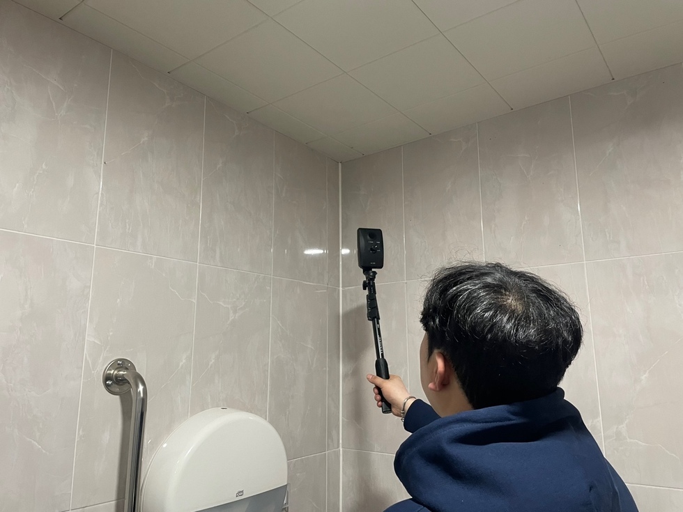 공용화장실 벽을 점검하는 남성 직원의 모습