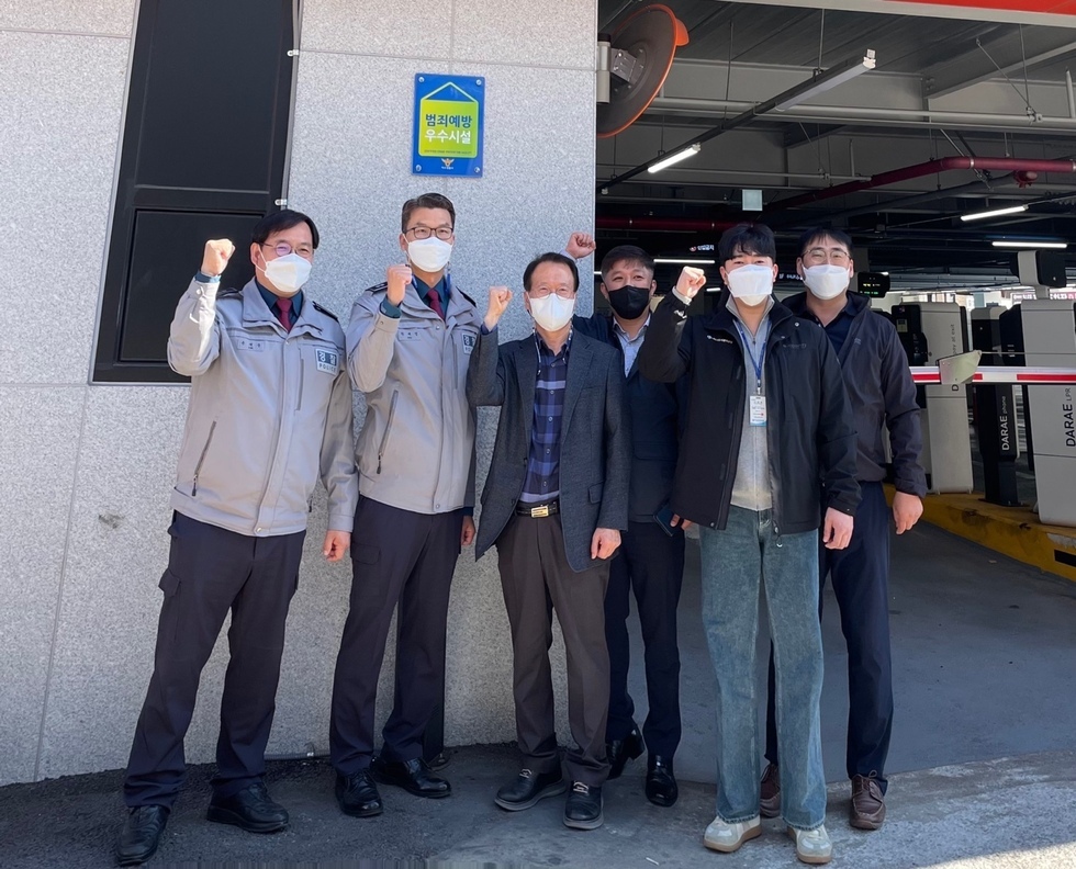 공영주차장 입구 벽면에 현판을 걸고 관계자들 여러명이 화이팅포즈를 취하며 기념촬영을 하는 모습