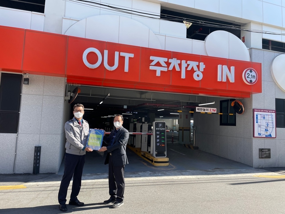 공영주차장 앞에서 범최예방 우수시설 현판을 들고 관계자들이 기념촬영을 하는 모습