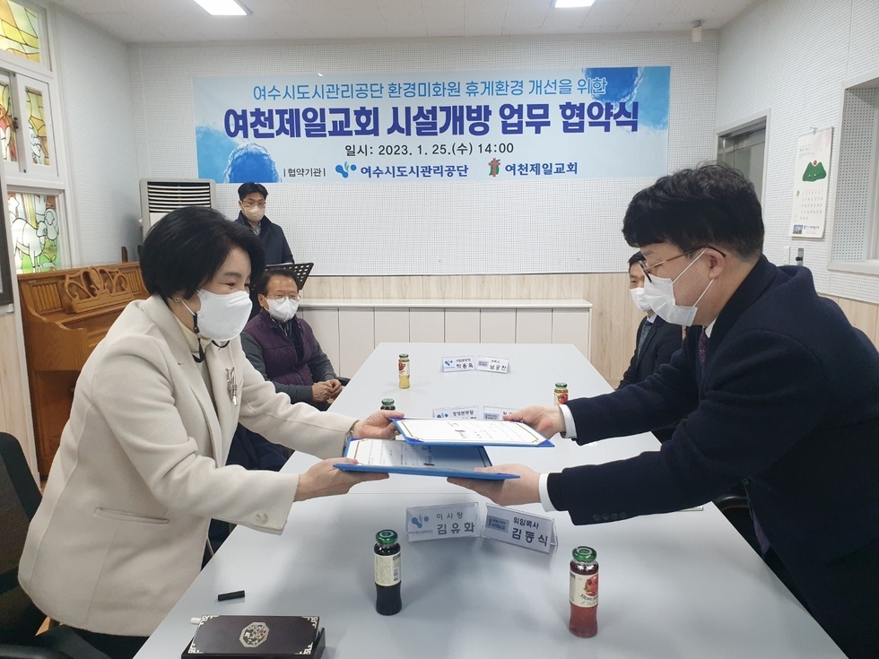 여천제일교회 시설개방 업무협약식에 참석한 여수도시관리공단 김유화 이사장과 여천제일교회 김동식 위임목사가 협약서를 건내는 모습