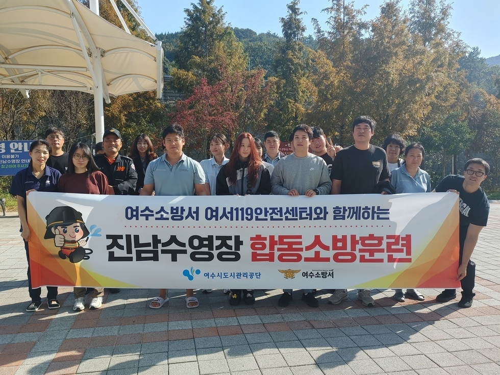 여수소방서 여서119 아넞ㄴ센터와 함께하는 / 진남수영장 합동 소방훈련 / 여수도시관리공단 / 여수 소방서 가 적힌 현수막 뒤로 관계자들이 서서 사진을 찍고 있는 모습