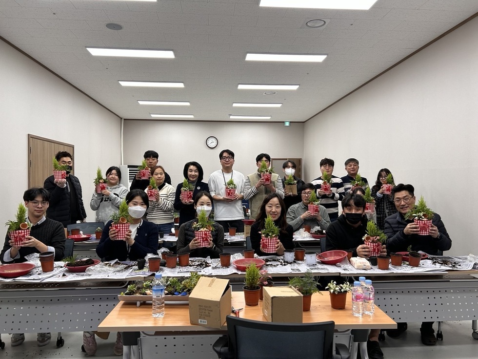 공단 관계자들이 화분을 들고 앉아서 사진을 찍고 있는 모습