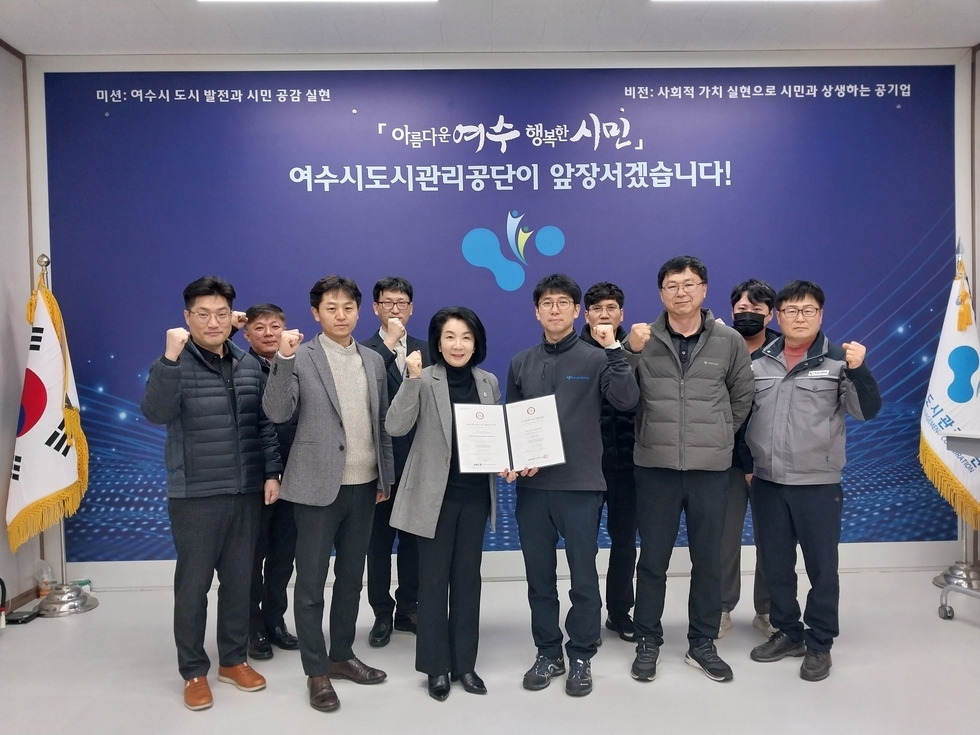 보란색 배경에 흰색으로 아름다운 여수 행복한 시민 / 여수도시관리 공단이 앞장서겠습니다! 씌여진 곳 앞에서 관계자들이 서있는 모습