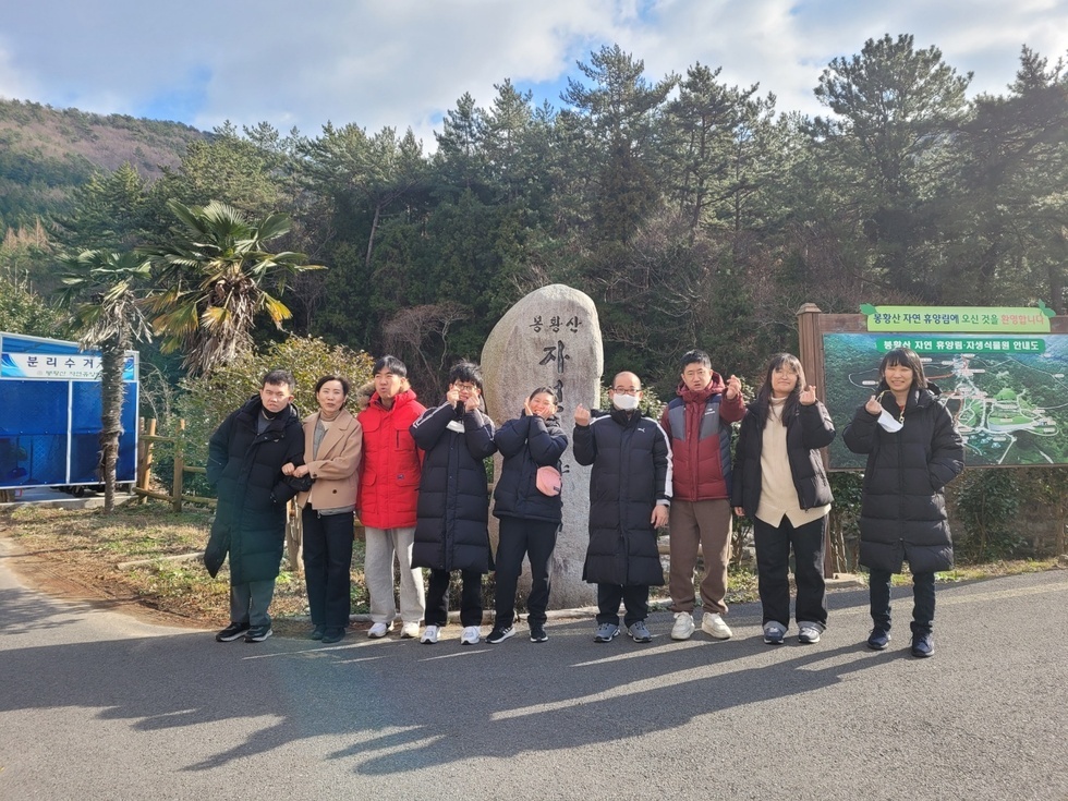 봉황상 자연휴양림 앞에서 9명의 사람들이 사진을 찍고 있는 모습