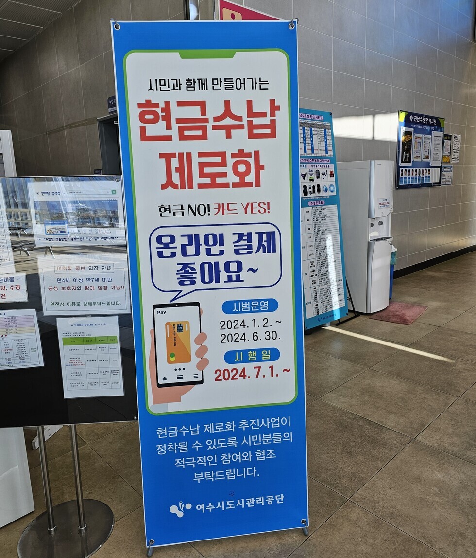 시민관 함께 만들어가는 / 현금 수납 제로화 / 현금 No! 카드 YES! / 온라인 결제 좋아요~ / 시범 운영 (2024.1.2 ~ 2024.6.30) / 실행일 (2024.7.1~) / 현금 수납 제로화 추진 사업이 정착될 수 있도록 시민분들의 적극적인 참여와 협조 부탁드립니다. / 여수 도시관리공단 이라는 내용이 적힌 세로 현수막 사진