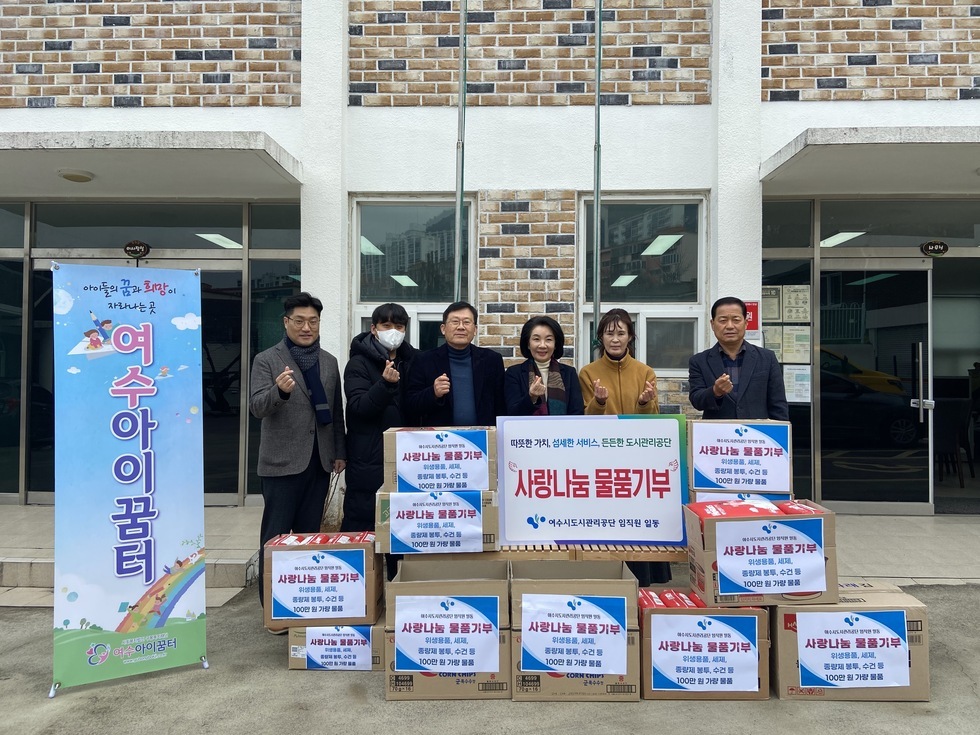 사랑나눔 물품 기부라는 용지가 붙은 박스들 뒤에서 공단 및 기관 관계자들이 일렬로 서  있는 모습