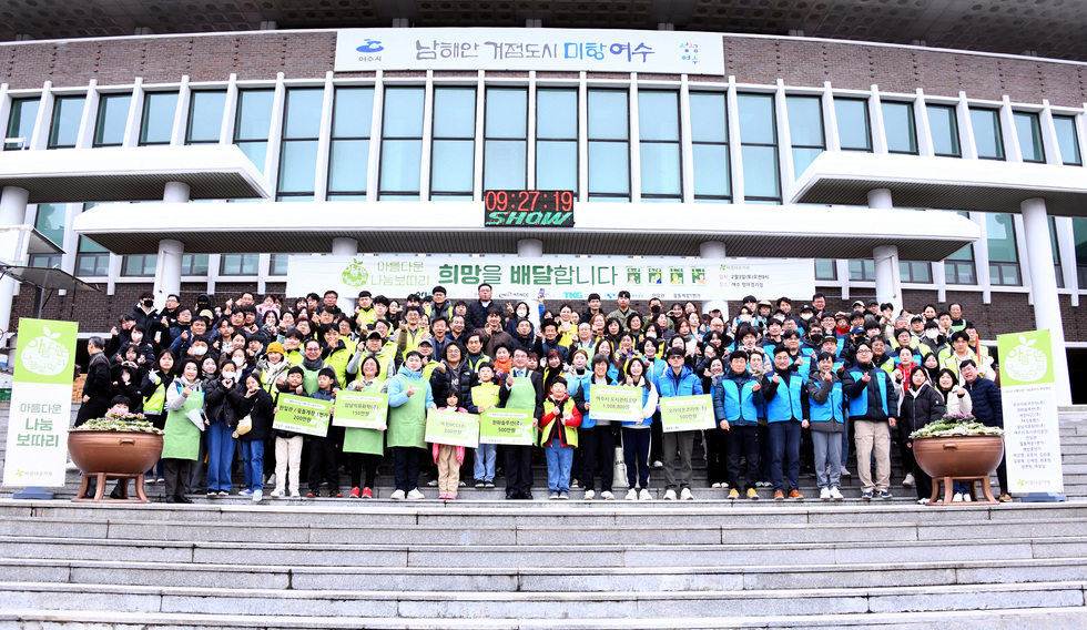 파란 색 옷을 입은 공단관계자들과 녹색 옷을 입은 아름다운 가게 관계 자들이 계단위에서 사진을 찍고 있는 모습