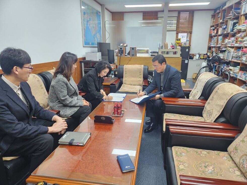 여수동광교회 관계자와 공단 관계자가 테이블에 앉아 서명을 하고 있는 모습