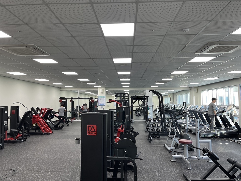 여러개의 운동기구들이 놓여있는 헬스장에서 한 여성과 남성이 운동을 하고 있는 모습을 찍은 사진이다.