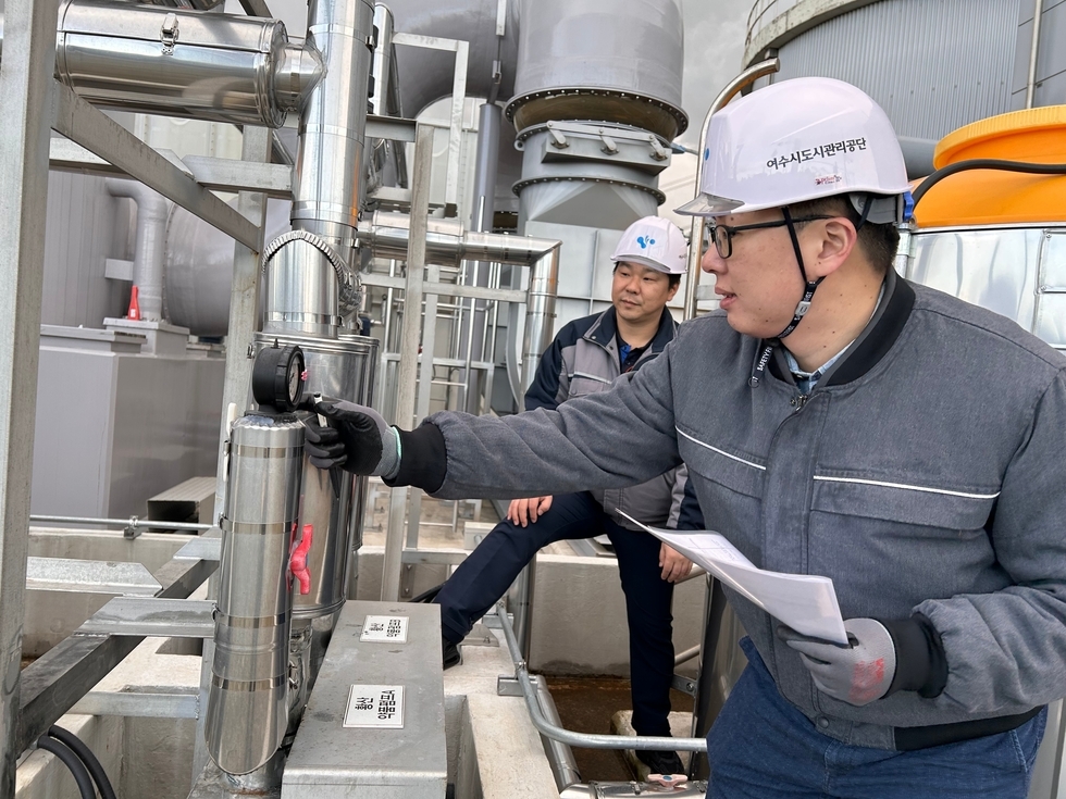 두 명의 중년남성이 '여수시도시관리공단' 문구가 적힌 안전모를 쓰고 '황산 약품펌프 A'가 문구가 붙어있는 기계를 점검하고 있는 사진이다.
