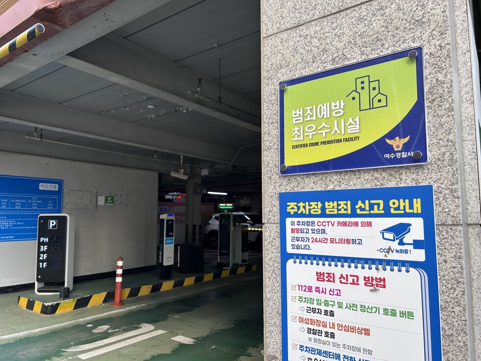 `범죄예방 최우수시설 CERTIFIED CRIME PREVENTION FACILITY 여수경찰서` 팜플렛과 주차장 범죄신고 안내 포스터가 붙어있는 주차장 출입구 사진