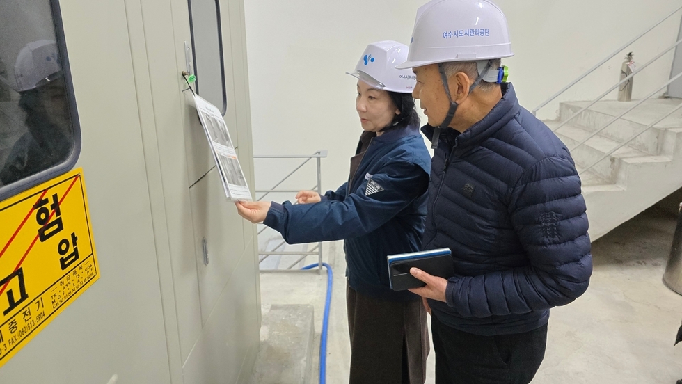 여수도시관리공단 김유화 이사장님과 직원 한명이 '위험/고압' 문구가 적힌 문 앞에서 안전모를 쓰고 안전점검표를 확인하고 있는 사진이다.
