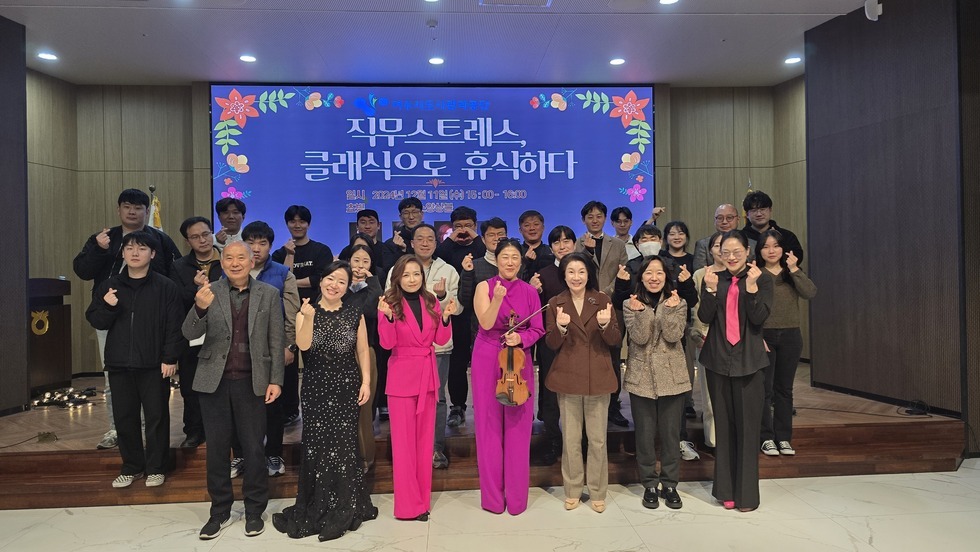 행사 종료 후 단체 기념 촬영 모습이다. 화면의 스크린에는 여수시도시관리공단 직무스트레스, 클래식으로 휴식하다 일시 2024년 12월 11일 (수) 15:00 ~ 16:00 쵸빙 룩스앙상블 바이올린 이은주 첼로 김채연 피아노 김수현 소프라노 안온유 라는 문구가 적혀있는 화면이 띄워져 있으며  30여명의 임직원들과 쵸빙 악단이 손가락 하트를 하며 포즈를 취하고 있다. 