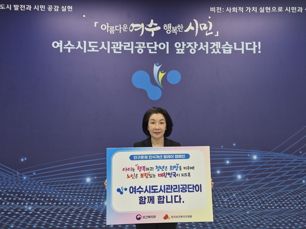 '아름다운 여수 행복한 시민 여수시도시관리공단이 앞장서겠습니다!' 라는 문구가 적힌 보라색 배경 앞에서, 여수시도시관리공단 이사장이  팻말(인구문제 인식개선 릴레이 캠페인 아이는 행복하고 청년은 희망을 키우며! 노인은 보람 있는 대한민국이 되도록 여수시도시관리공단이 함께 합니다. 보건복지부 한국보건복지인재원)을 들고 기념 촬영을 하는 모습